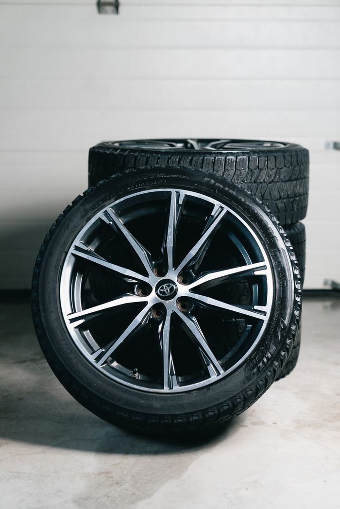 about-01 Close-up of stacked car tires and alloy wheels in a garage setting, showcasing automotive equipment.