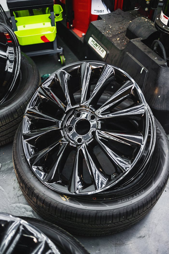 services-02 Glossy black car wheel rim and tire stack in an automotive workshop.