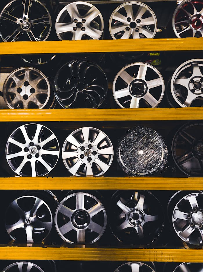 hero-img-01 Vertical shot of various car rims displayed on shelves in Malaysia, showcasing different designs.